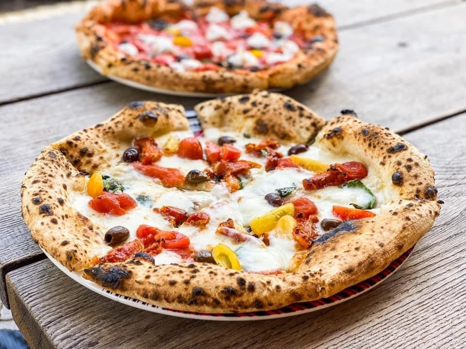 Chef reheating pizza slices on skillet for crispy crust at a mobile pizza catering event
