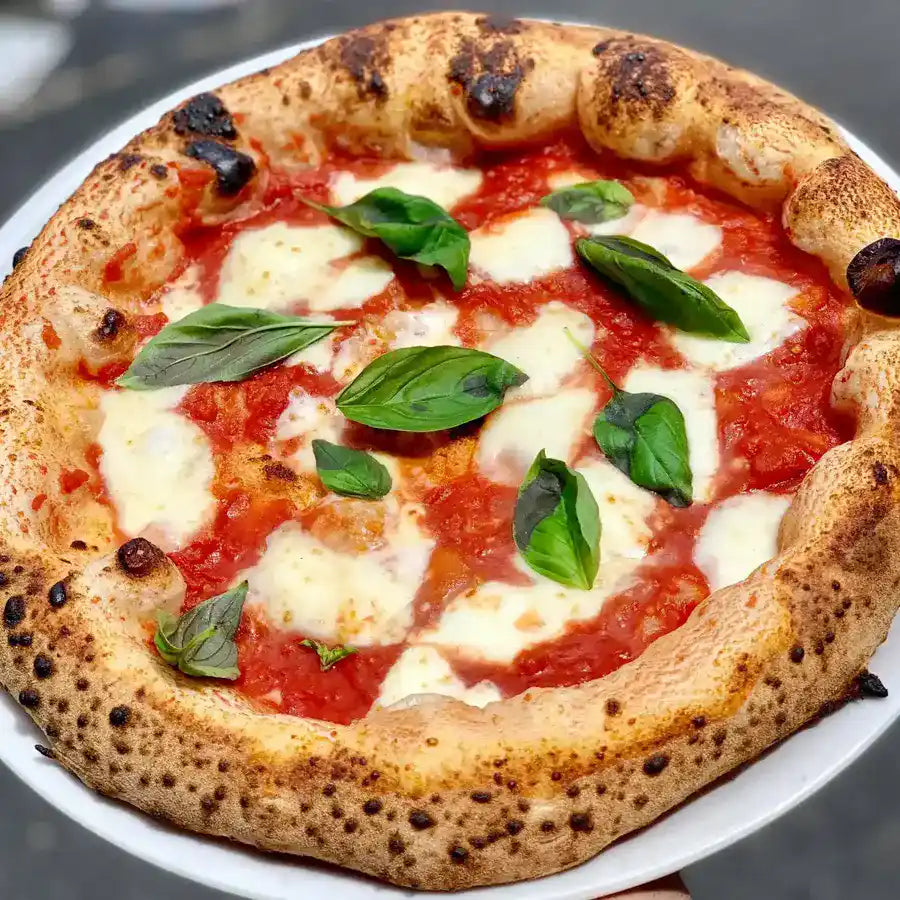 Fresh red base pizza topped with cheese and herbs at Pizzeria On The Road