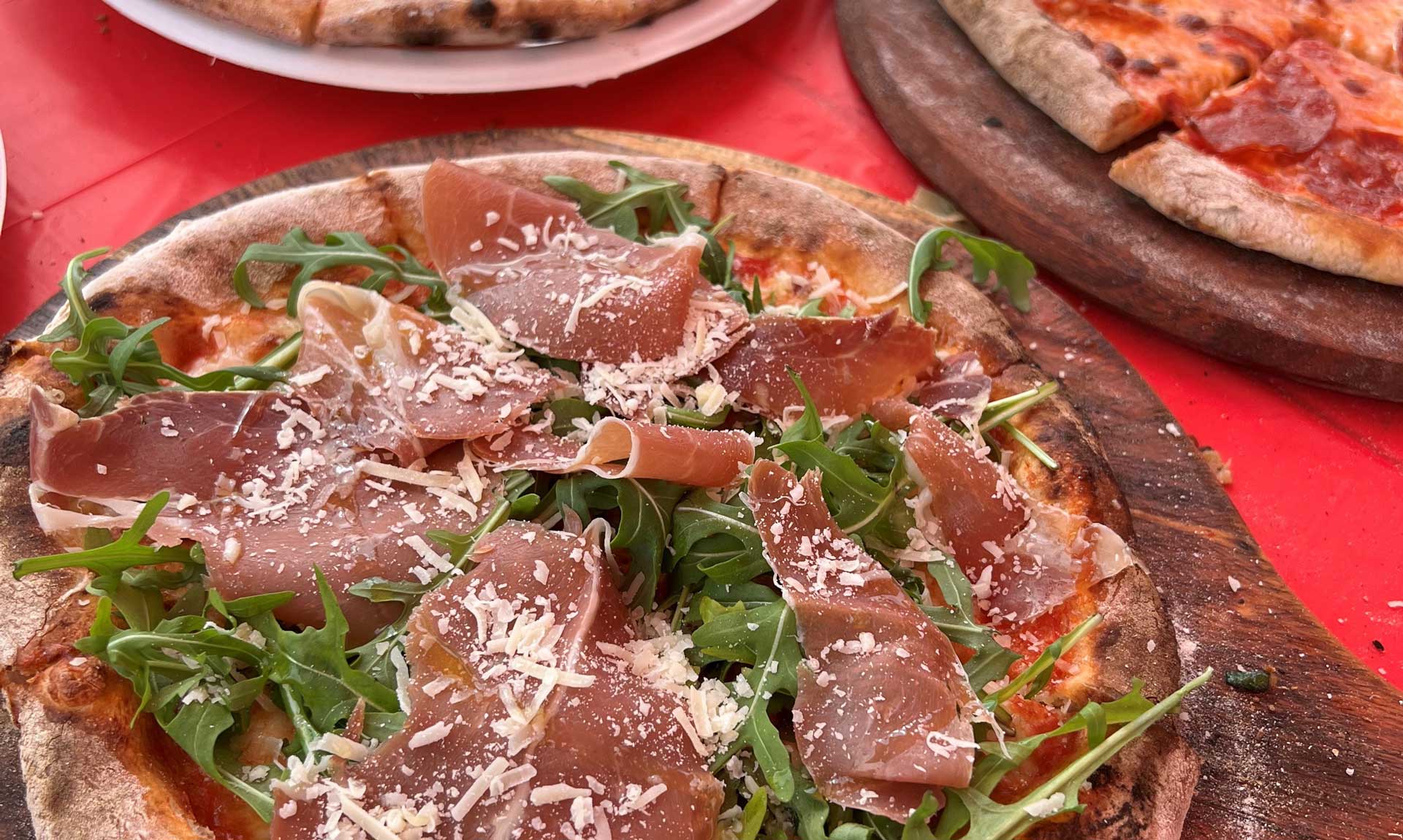 Pizza topped with assorted meat and fresh ingredients at Pizzeria On The Road